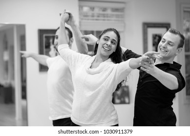 Dance teacher and ballroom dancers looking in mirror. Mixed race young woman dance with partner