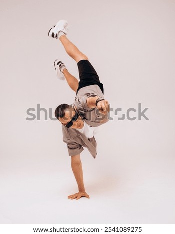 dancer doing acrobatic trick and dancing breakdance, young energetic guy stands on his hands in unusual pose