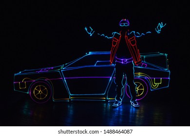 Dancer In Led Suit Near Neon Car .