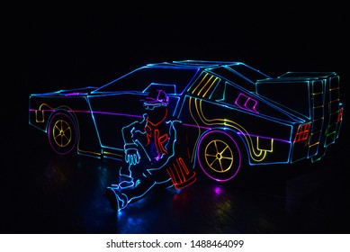 Dancer In Led Suit Near Neon Car .