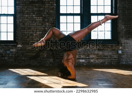 Dancer leg extension in shoulder stand in rustic building