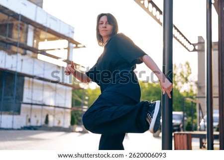 Dancer performs expressive movement outdoors in urban setting during golden hour