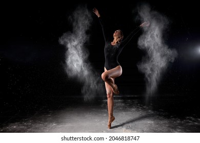 Dancer posing dancing gracefully in studio with cloud of dust, flour. Dancer in black bathing suit is moving, in action, having good choreographic training. ballet, dance, performance, art