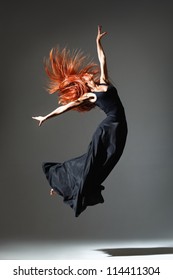 Dancer With Red Hair Jumping Over Dark Grey Background