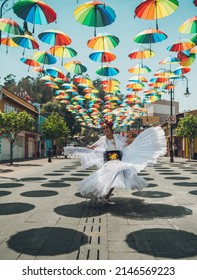 Dancer of typical Mexican dances from the region of Veracruz, Mexico, doing her performance in the street adorned with colored umbrellas.