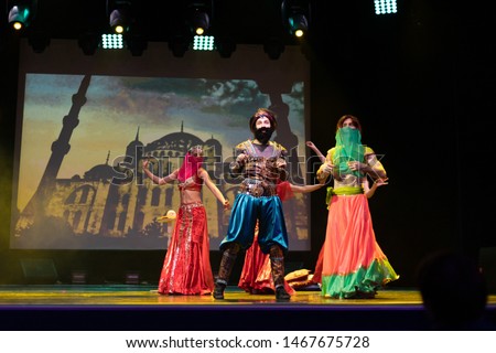 Dancers actors in Oriental Bellydance costumes perform in theater on stage in a dance show.