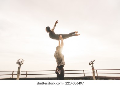 Dancers Couple Posing An Acrobatic Lift On A Cliff At Sunset Kissed By The Sun