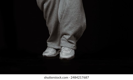Dancer's Feet in Grey Sweatpants and White Sneakers of close up
