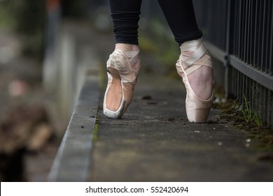 A Dancers Feet On Pointe Wearing Ballet Shoes Outdoors.