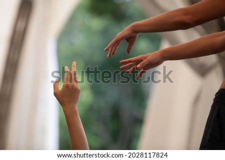 dancers' hands stretches into space against a background of natural greenery in contact improvisation intentionally with motion blur ond defocus bokeh