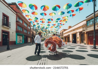 Dancers of typical Mexican dances from the central region of Mexico, doing their performance in the street adorned with colored umbrellas.