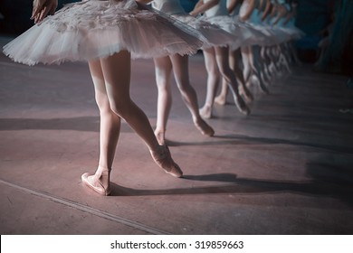 Dancers in white tutu synchronized dancing on stage. Repetition.
