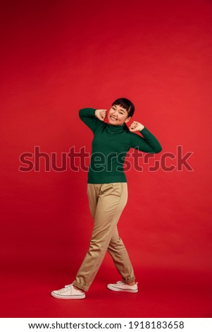 Dancing cheerful, smiling. East asian young beautiful woman's portrait on red background with copyspace. Brunette female model. Concept of human emotions, facial expression, sales, ad, fashion.