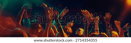 Dancing crowd silhouettes under dramatic concert lighting. Concept of shared emotions, rhythmic movement, social connection, music immersion and Christmas night celebration atmosphere. Banner