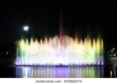 A dancing fountain or a fountain that is formed by controlling the ups and downs and has a light tone green bright.  And the color reflecting on the water.