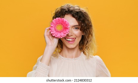 Dancing Happy Young Woman Smiling Twirls Pink Flowers Near her Eyes Close Up on Yellow Background. Portrait of Glamorous, Beautiful Sweet Girl Positive Emotions people. Fashion. Monotone