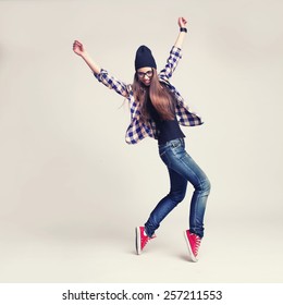 Dancing Hipster Girl In Glasses And Black Beanie On Light Background