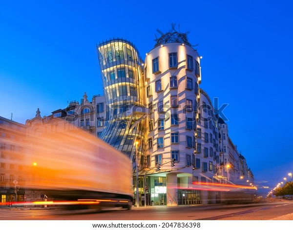Dancing house in Prague at night with\
glowing strips of car lights , Czech republic. Travel and sights of\
city breaks. landmarks, travel guide and\
postcard