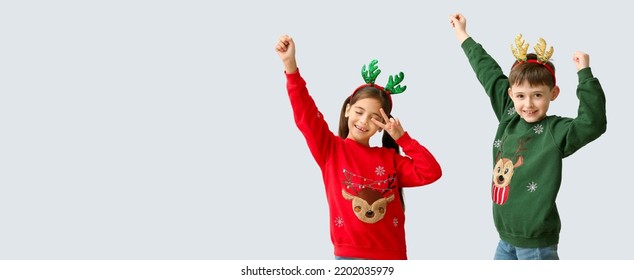 Dancing little children with reindeer horns on light background with space for text