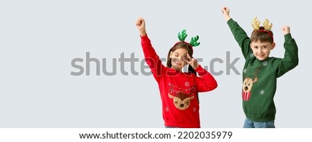 Dancing little children with reindeer horns on light background with space for text