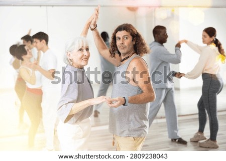 Dancing positive couple learns a slow foxtrot in a lesson in a dance studio