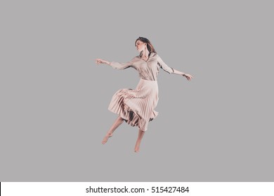 Dancing queen. Studio shot of attractive young woman in beautiful dress hovering in air