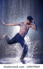 Dancing in the rain. Young male dancer in black fedora dancing in the rain