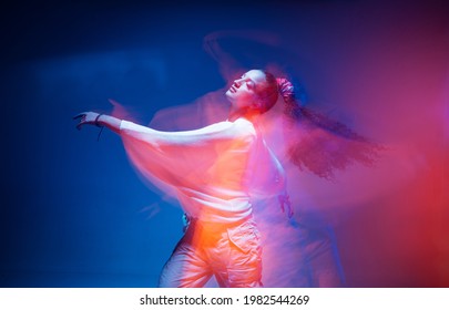 Dancing young mixed race girl enjoying moving in colorful neon studio light. Long exposure. Ethnic fiery dance - Powered by Shutterstock