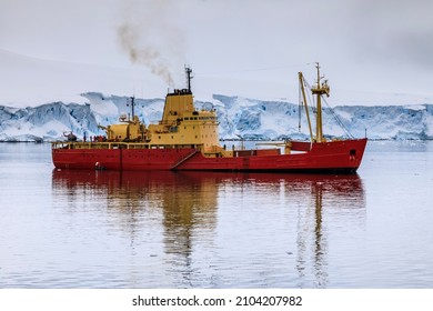 Danco Coast, Antarctica - 12 09 17: Antarctic Icebreaker Supply Ship With People And Helicopter On Deck Providing Logistics Support To An Antarctic Station With A Scenic View Of Blue Ice Glaciers