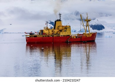 Danco Coast, Antarctica - 12 09 17: Chilean Navy Diesel Electric Antarctic Icebreaker Ship Almirante Oscar Viel With People And Helicopters On Deck And Reflections In Paradise Bay With Misty Mountains