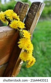 Dandelion wreath made of fresh flowers hanging on old wooden horse cart