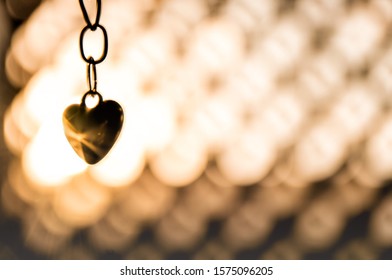 dandling heart chain in front of sun  - Shutterstock ID 1575096205