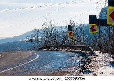 Dangeorus road bend on spring time, melting snow on asphalt.