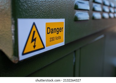 Danger 230 volts sign on a green metal street cabinet