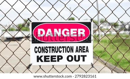 Danger construction area keep out sign hanging on a chain link fence