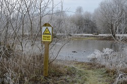 'Danger Deep Water' Sign Beside A Frozen Pond On A Frosty Winter Day. UK
