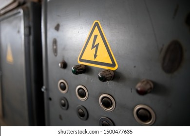 Danger of electrocution yellow sign on gray background. High voltage warning sign. Electric bolt in yellow triangle safety symbol: caution, risk of electric shock.