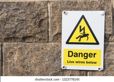 Danger Live Wires Below Warning Sign On A Stone Brick Wall