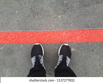 Danger. Man Legs In Black Shoes Standing Behind The Red Line