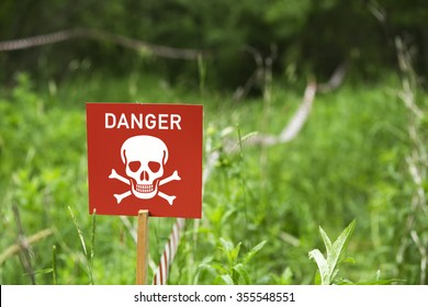 Danger Of Mines Or Toxic Poison Sign On A Field