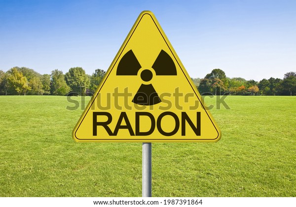 Danger\
of radioactive contamination from RADON GAS - concept with warning\
symbol of radioactivity on road sign against a building lot and\
vacant land available for building\
construction.