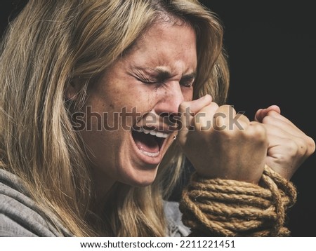 Danger, scared and horror woman scream for help with hands tie and trapped by rope on black studio background. Violence, sad or anxiety female with crime, fear and prisoner, crying for mental health