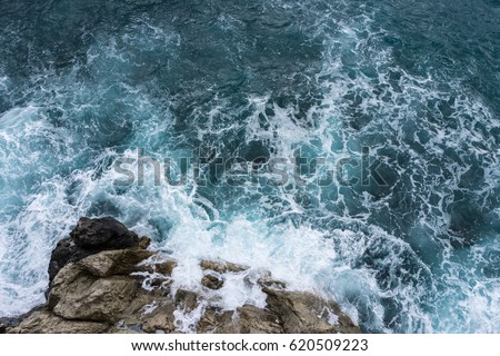 Danger sea wave crashing on rock coast with spray and foam before storm in Positano, Italy