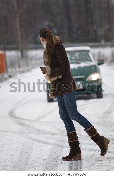 danger situation - woman crossing the road, car\
drives on snowy street