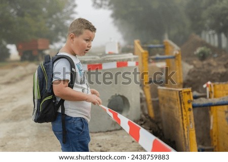 danger to students. a school boy comes across an excavation due to sewer digging works.the danger of going to school independently.construction works. warning and danger for children going to school