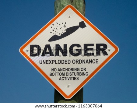 Danger unexploded ordnance post brilliant blue sky