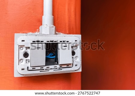 Dangerous broken electricity outlet socket and light switch on wall hole. Old damaged and broken electric switches and socket without cover on concrete wall. Power outlet sockets without the covering.