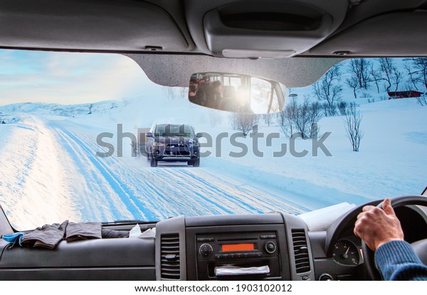 Dangerous car ride through snowy mountains areas.\
A view from the driver\'s angle to car interior and road - Landscape\
of car on road in snowy\
winter