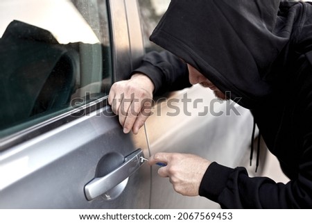 Dangerous Car thief steal car breaking door criminal job burglar Hijacks Auto thief is trying break into automobile using tools. Street crime violence gangster robber automobile parking