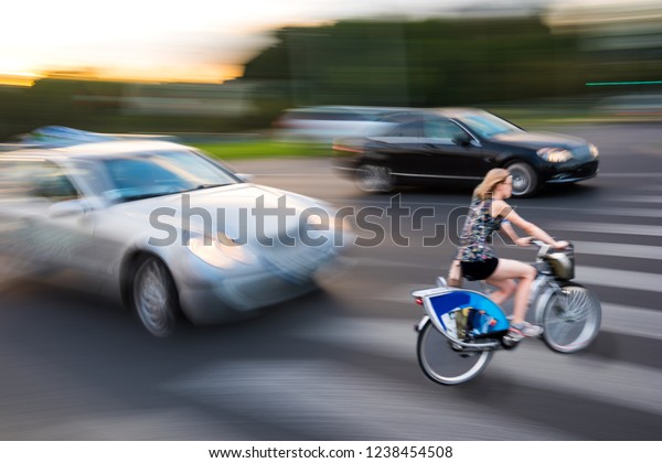 Dangerous city traffic situation with cyclist and\
car in the city in motion\
blur